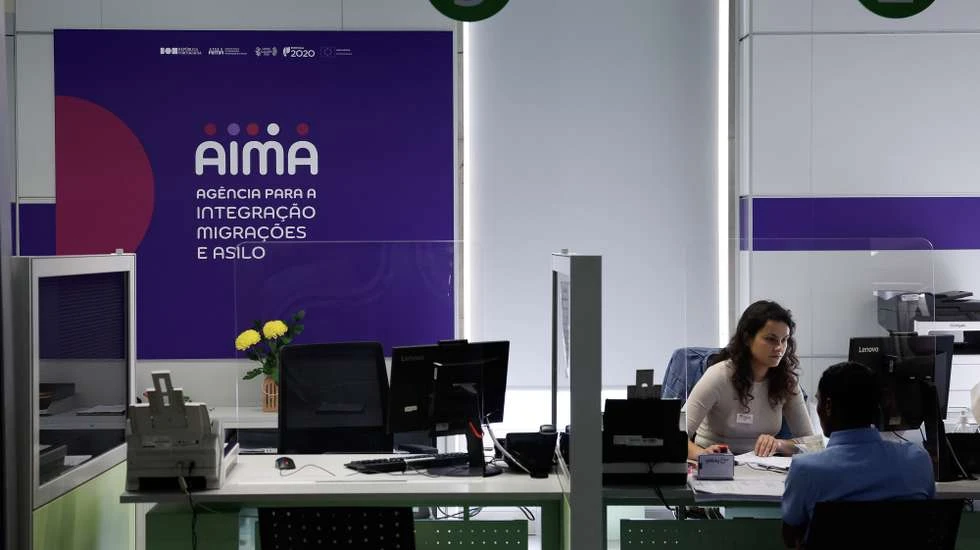 An AIMA officer advising a visitor at the counter — booking an AIMA appointment