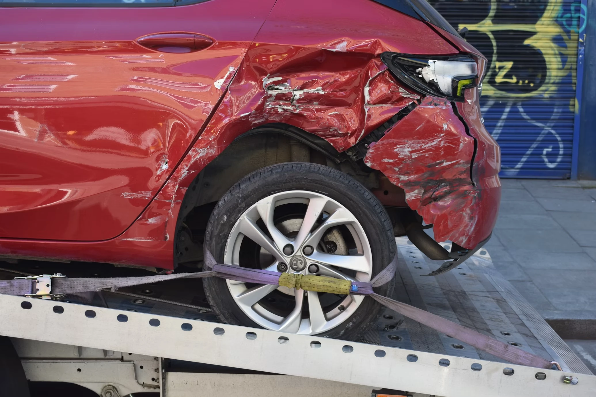 A red car damaged in an accident on a tow truck — insurance in Portugal